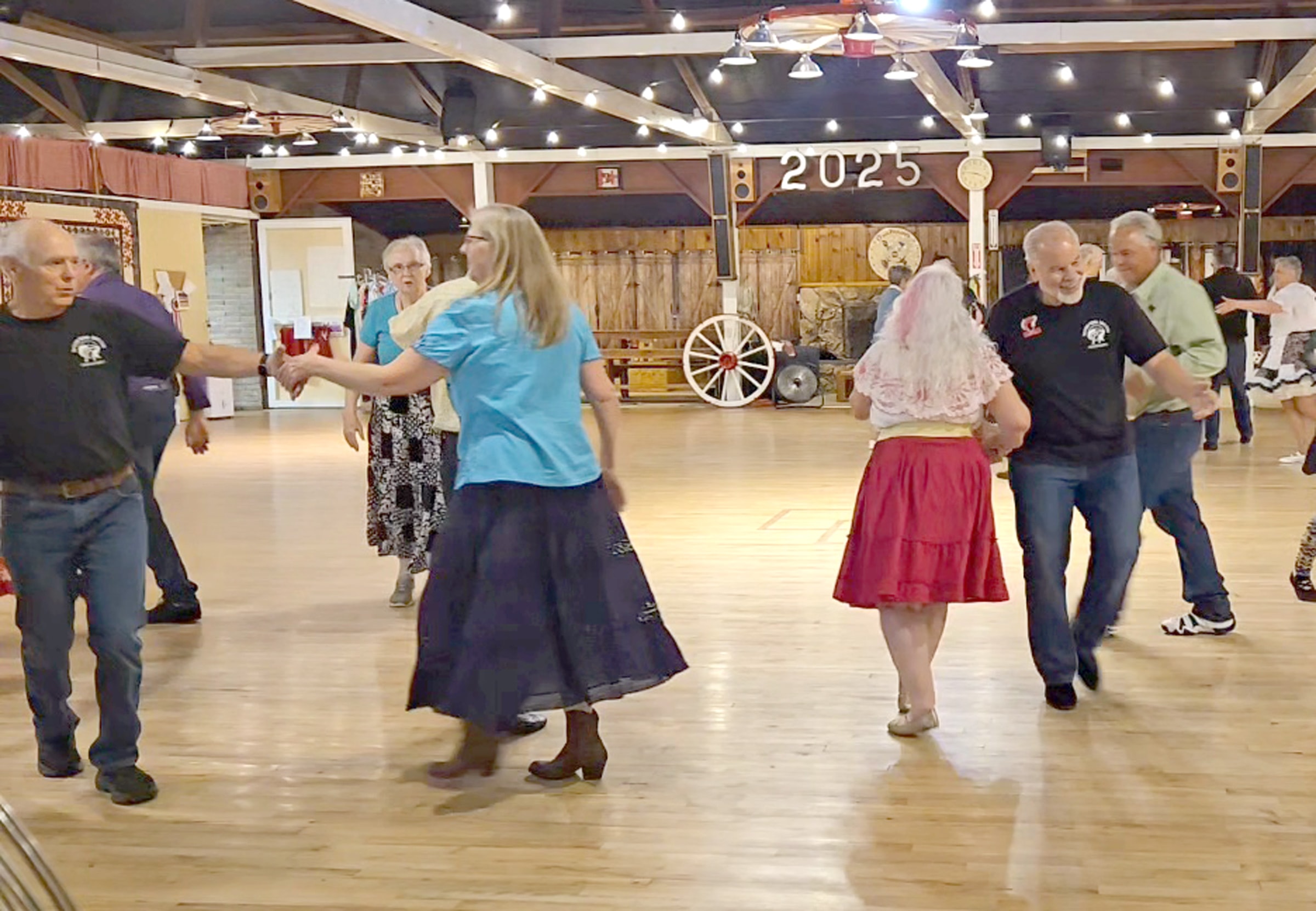 Square dance caller leading couples in red skirts and western attire in Roseburg, Oregon