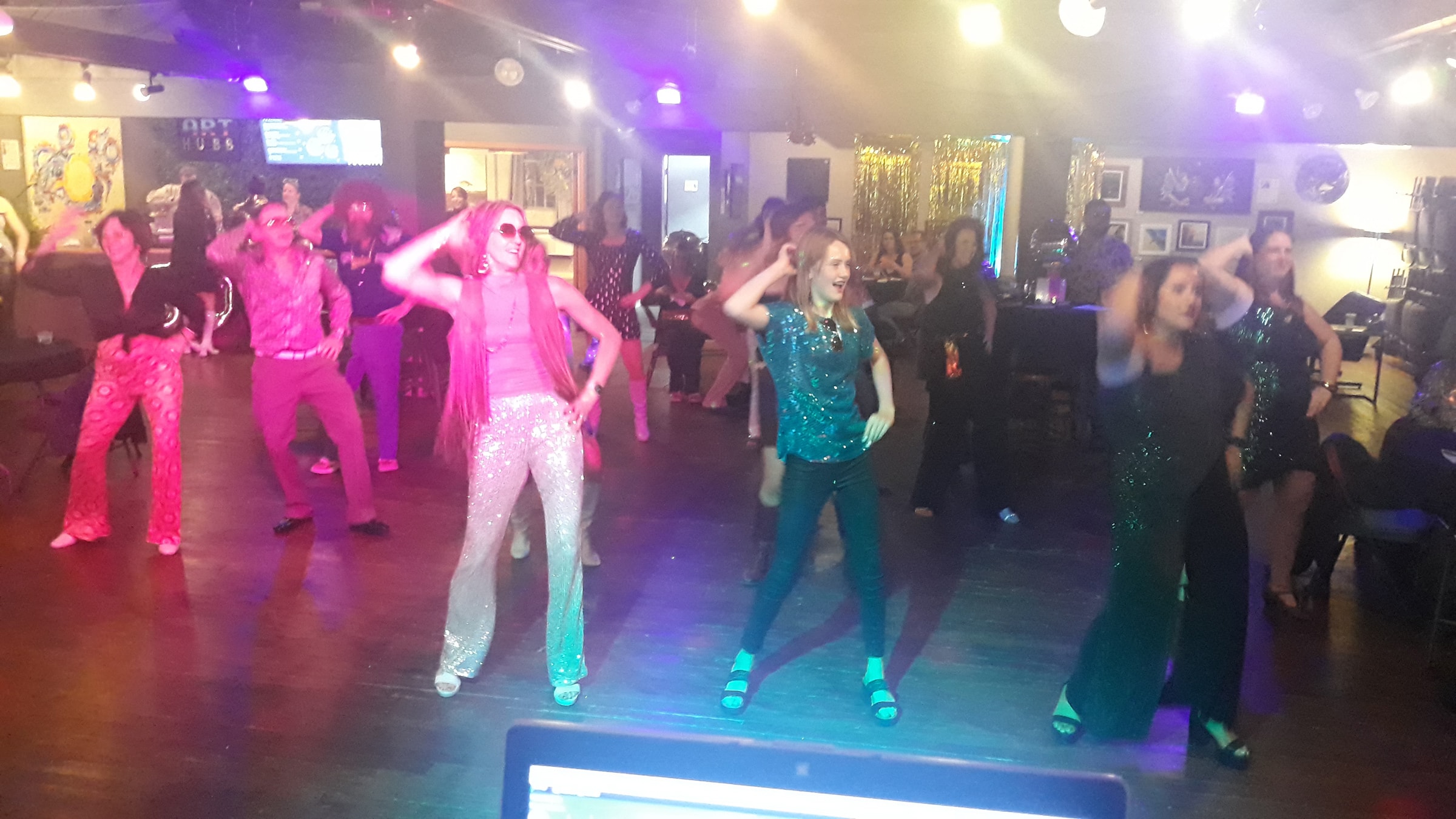 Guests in sequined outfits dancing at a 70s disco party in Grants Pass, Oregon
