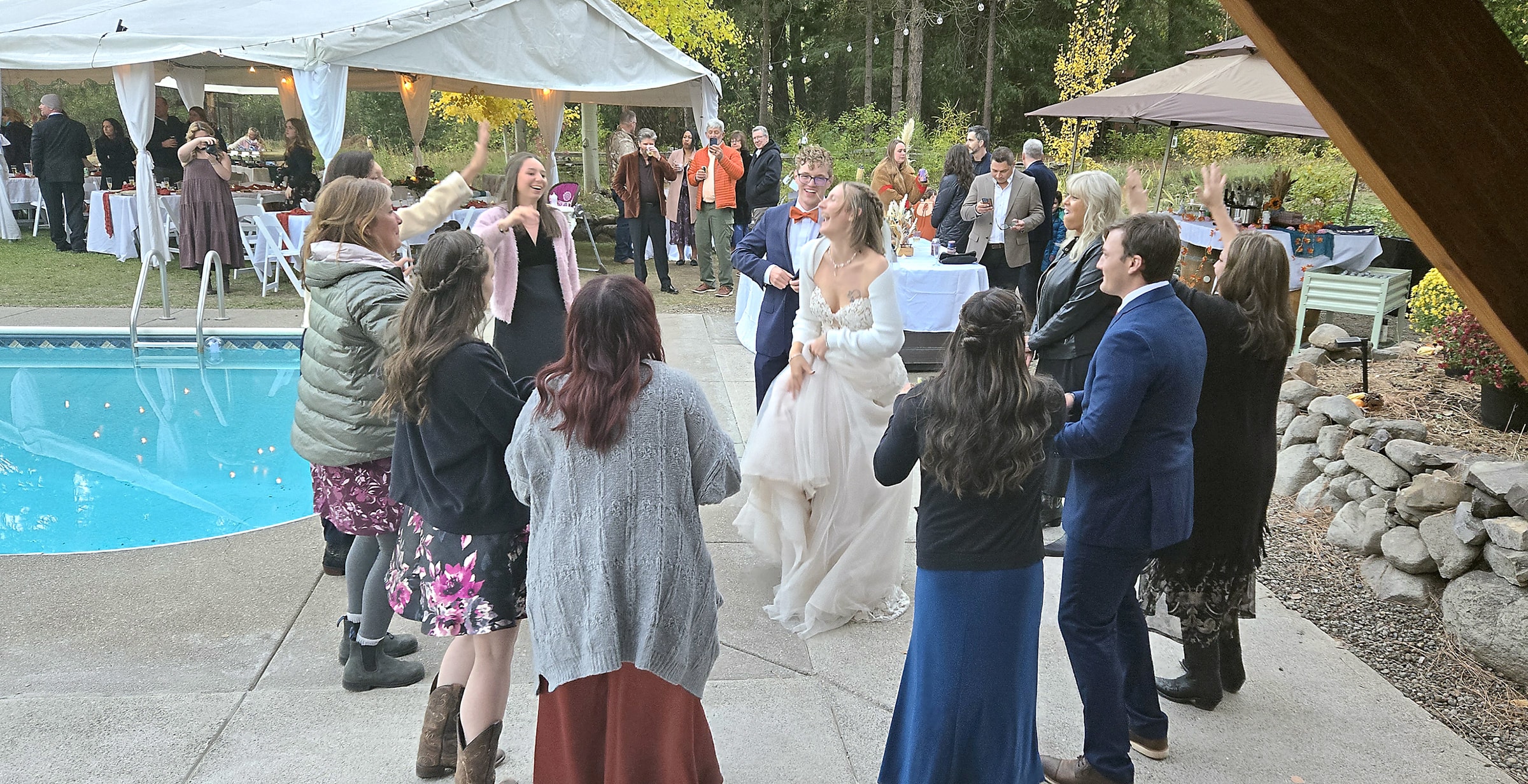 Bride dancing with guests at an outdoor poolside wedding reception in Ashland, Oregon