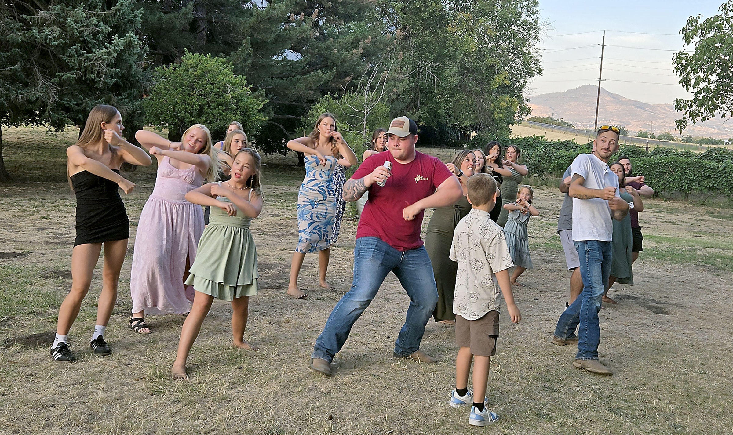 Wedding guests doing the Git Up novelty dance outdoors with a mountain backdrop in Central Point, Oregon