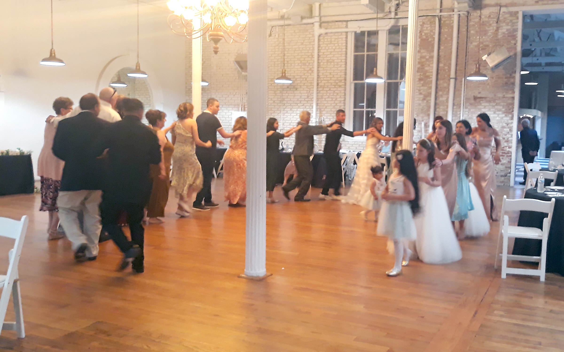 Bridesmaids and flower girls dancing together in a bright industrial venue in Northern California